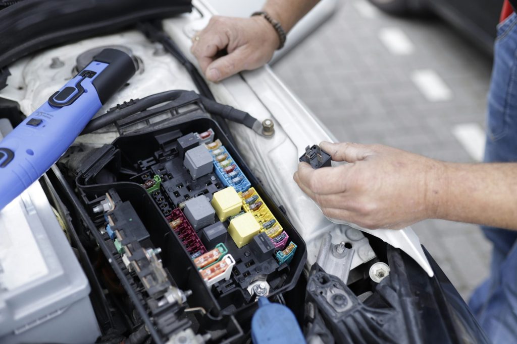 Un hombre está trabajando en el motor de un coche.